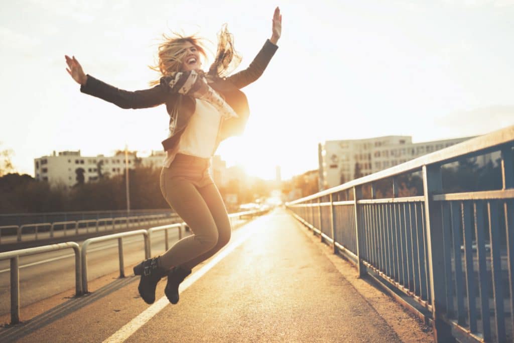 Happy woman outdoors feeling free in sunset