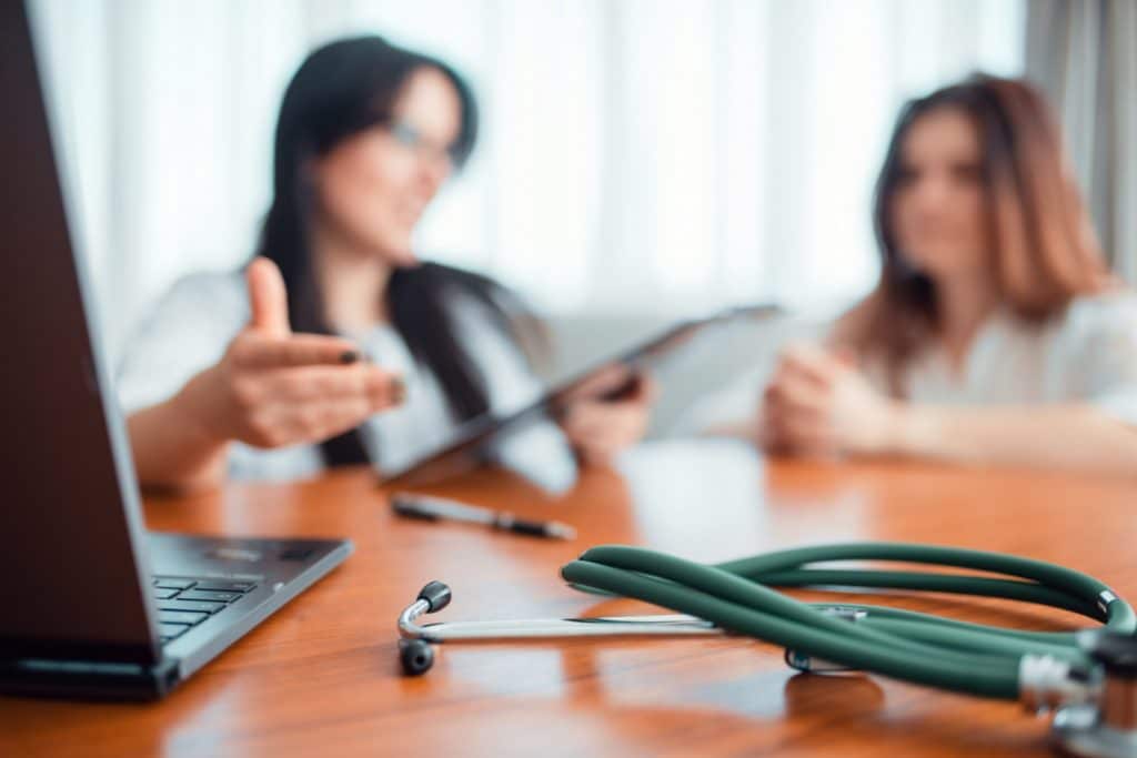 Closeup of stethoscope with blurred image of doctor and patient in background