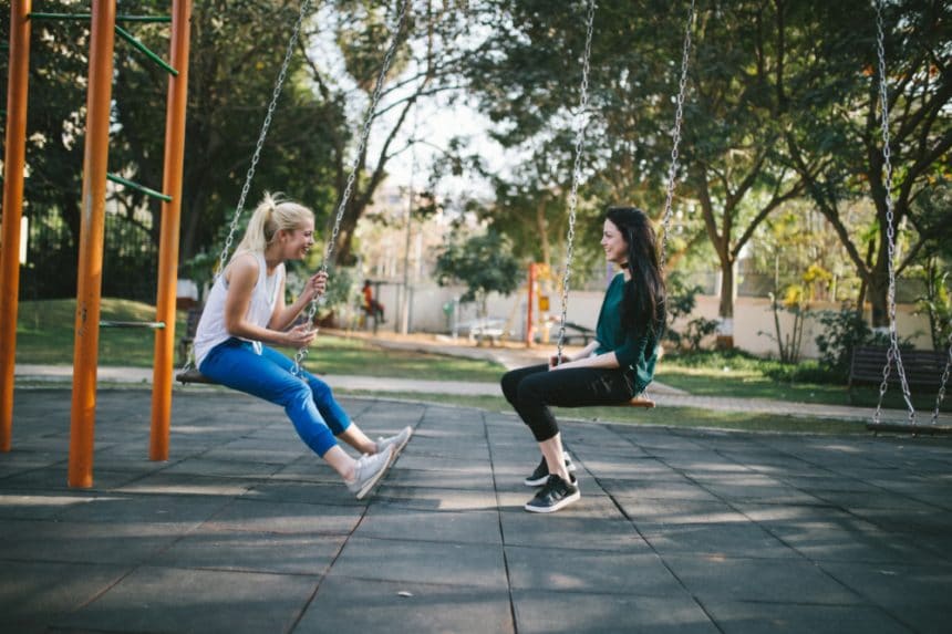 Two young women sitting on swings facing each other - Women's Health Manhattan NYC