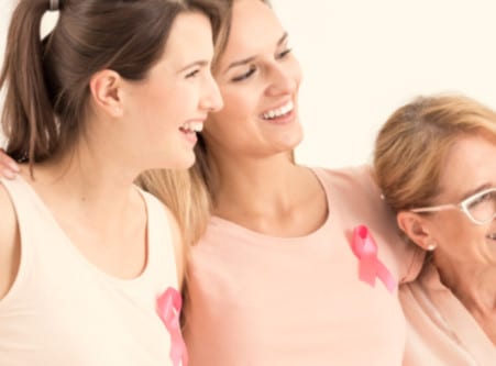 Women smiling with breast cancer support ribbon - Breast Cancer Manhattan New York