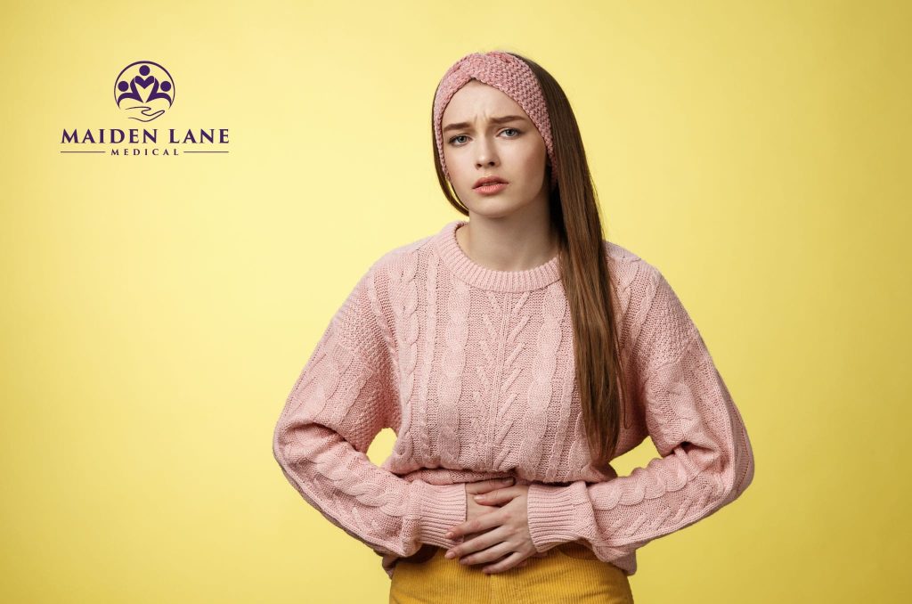 Woman expressing ovarian cyst pain and holding onto her lower belly.