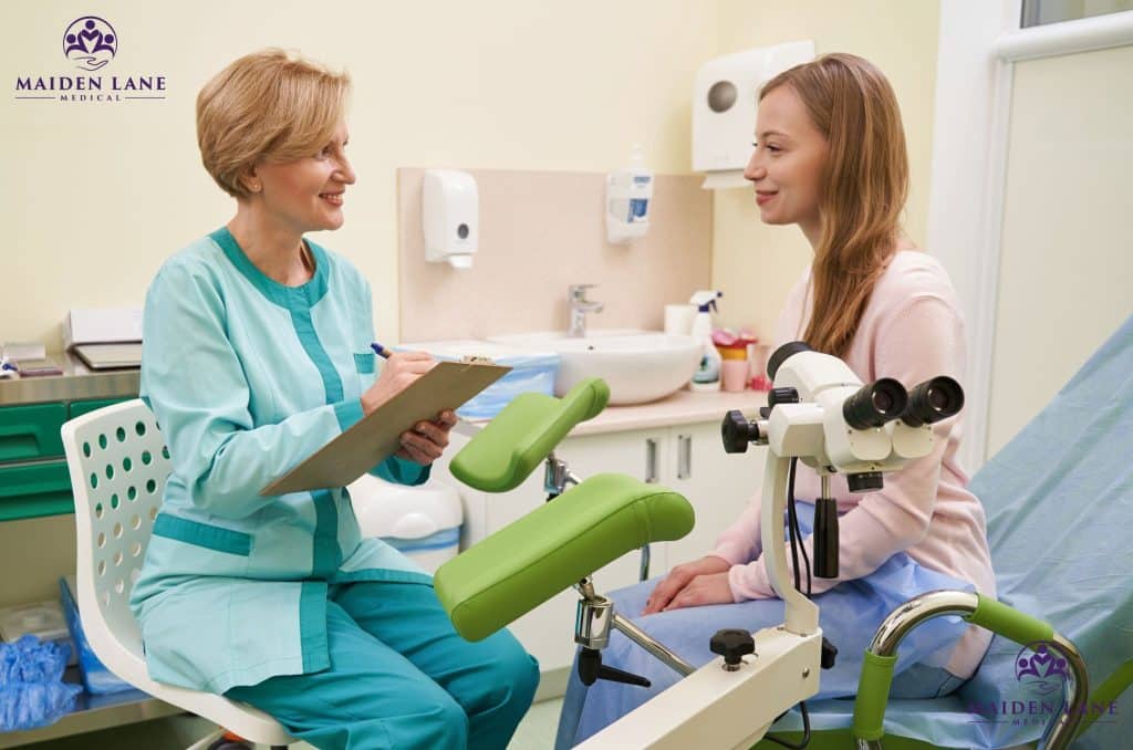 A gynecologist writing in chart while examining a patient before a mammogram.