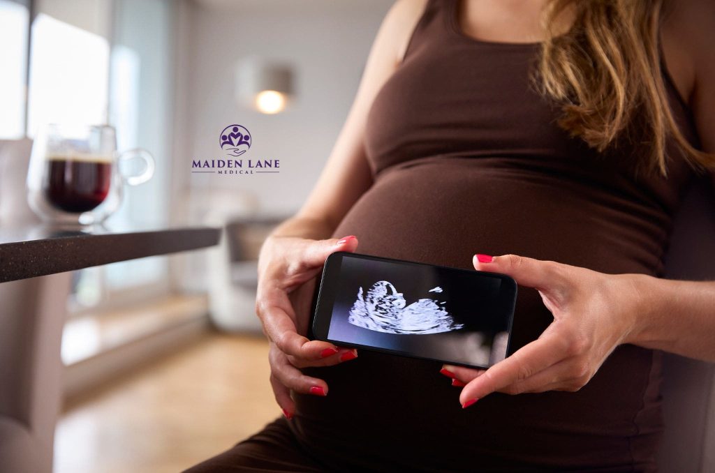 A pregnant woman showing an ultrasound image of her baby in her womb.